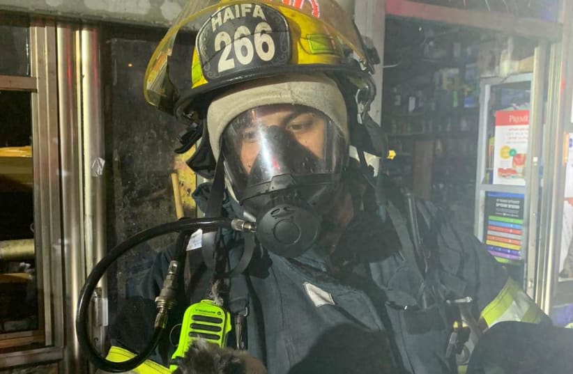 A firefighter holds an animal rescued from a Haifa pet store fire. (photo credit: FIRE AND RESCUE SERVICES HOF DIVISION SPOKESPERSON)