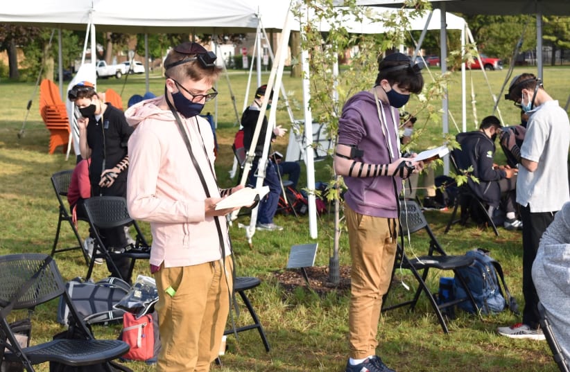 Students at the Ida Crown Jewish Academy pray in an outdoor service while wearing masks and maintaining social distance. The school has reopened with strict COVID protocols. (photo credit: EZRA LANDMAN-FEIGELSON)