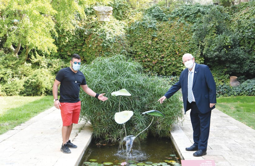 YARON MEYER and President Reuven Rivlin point to Meyer’s flower sculpture in the garden pool of the presidential compound. (photo credit: YARON GLASS)