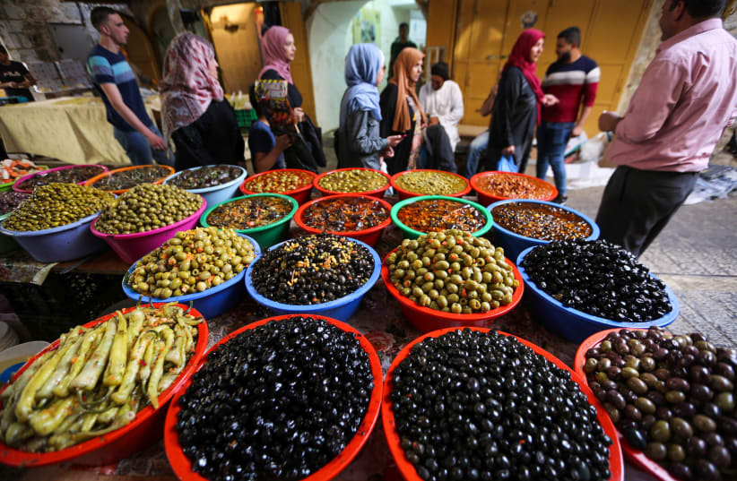 Palestinians buy food during the holy month of Ramadan, at a market in the West Bank city of Hebron, May 22, 2019. (photo credit: WISAM HASHLAMOUN/FLASH90)
