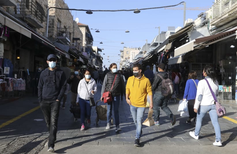 Shoppers are seen in Jerusalem's Mahane Yehuda, wearing masks in accordance with coronavirus restrictions, on November 29, 2020. (photo credit: MARC ISRAEL SELLEM/THE JERUSALEM POST)