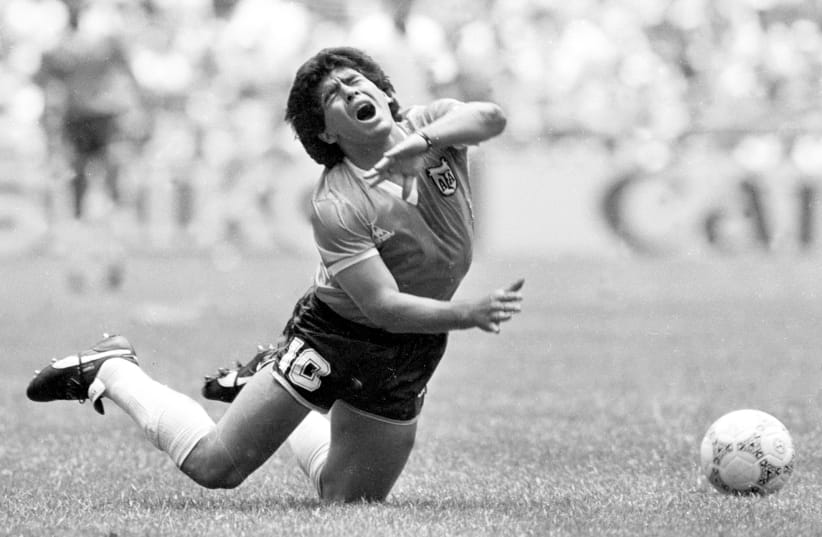 ARGENTINA’S DIEGO MARADONA falls during a World Cup match in Mexico City in 1986. (photo credit: GARY HERSHORN/REUTERS)