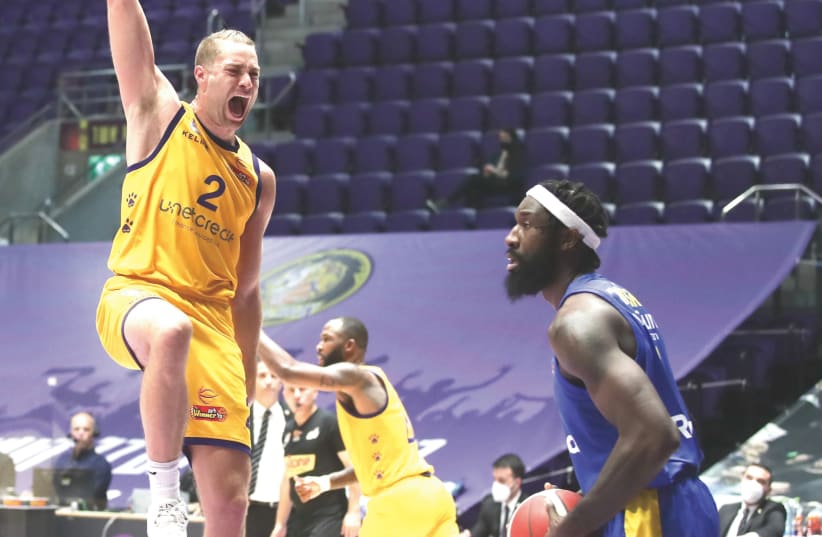 Hapoel Holon forward Willy Workman hangs from the rim after a dunk in the second half of his team’s 79-76 victory over Maccabi Tel Aviv in Winner League action (photo credit: DANNY MARON)