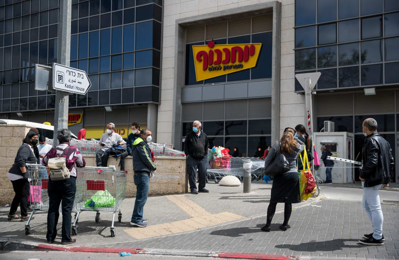People waiting in line outside Yochananof supermarket in Jerusalem on April 7, 2020. The government ordered on a partial lockdown, in order to prevent the spread of the coronavirus. (photo credit: YONATAN SINDEL/FLASH 90)