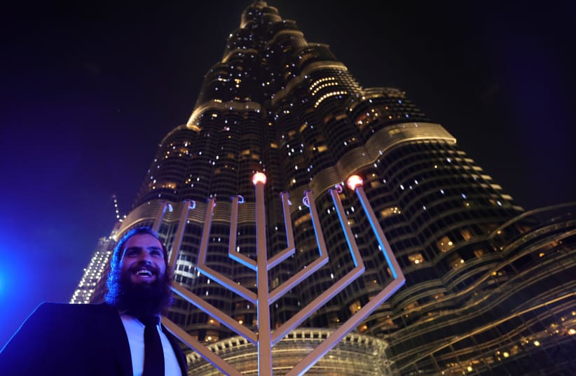 A man stands next to a giant menorah as people celebrate Hanukkah, the Jewish festival of lights, in Dubai, United Arab Emirates December 10, 2020. (photo credit: REUTERS/CHRISTOPHER PIKE)