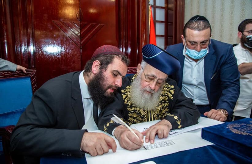 Israeli Chief Rabbi Yitzhak Yosef, center, writes part of a Torah scroll at the Jewish community center in Dubai, Dec. 19, 2020. At left is the center's leader, Rabbi Levi Duchman. (photo credit: COURTESY OF THE DUBAI JEWISH COMMUNITY CENTER)