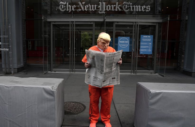 Mike Hisey dressed as US President Donald Trump in a prison jumpsuit reads ‘The New York Times’ in front of its office in Manhattan on September 28, after the paper reported that Trump paid only $750 in federal income taxes in the year he was elected president. (photo credit: CARLO ALLEGRI/REUTERS)