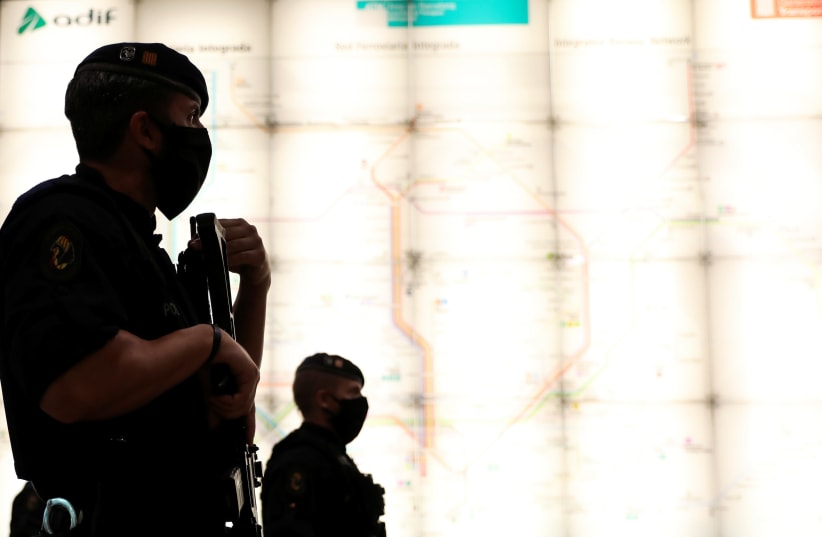 Police officers wearing protective masks patrol inside and empty Sants Estacio railway station, as the spread of the coronavirus disease (COVID-19) continues, in Barcelona (photo credit: REUTERS)
