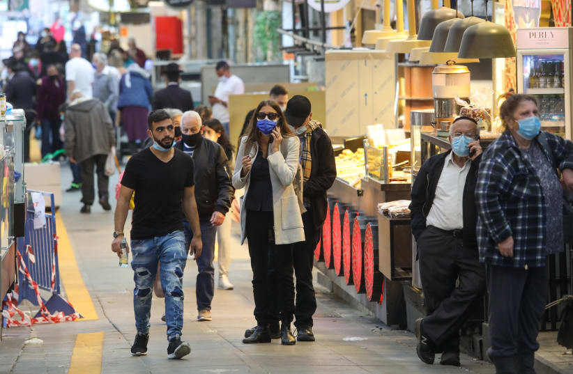 Israelis are seen walking in Jerusalem's Mahane Yehuda market amid the third coronavirus lockdown on New Year's Eve, December 31, 2020. (photo credit: MARC ISRAEL SELLEM/THE JERUSALEM POST)
