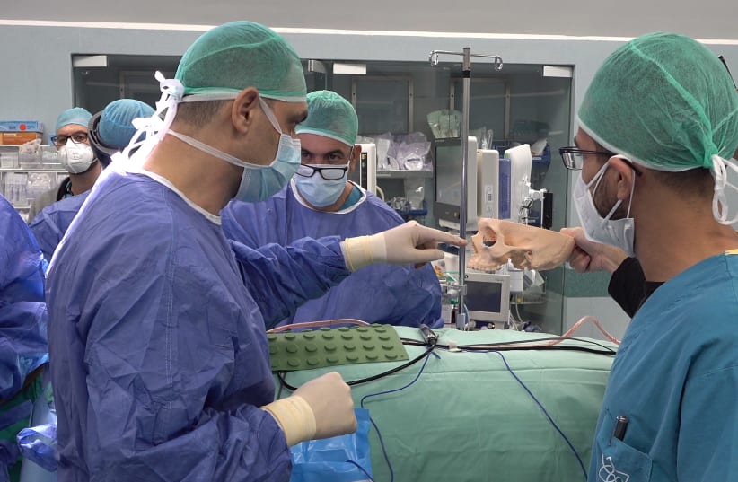 Surgeons are seen examining a model skull ahead of eye surgery using AR technology. (photo credit: ROEE BELCHENS/DENTAL PRO VIDEO)