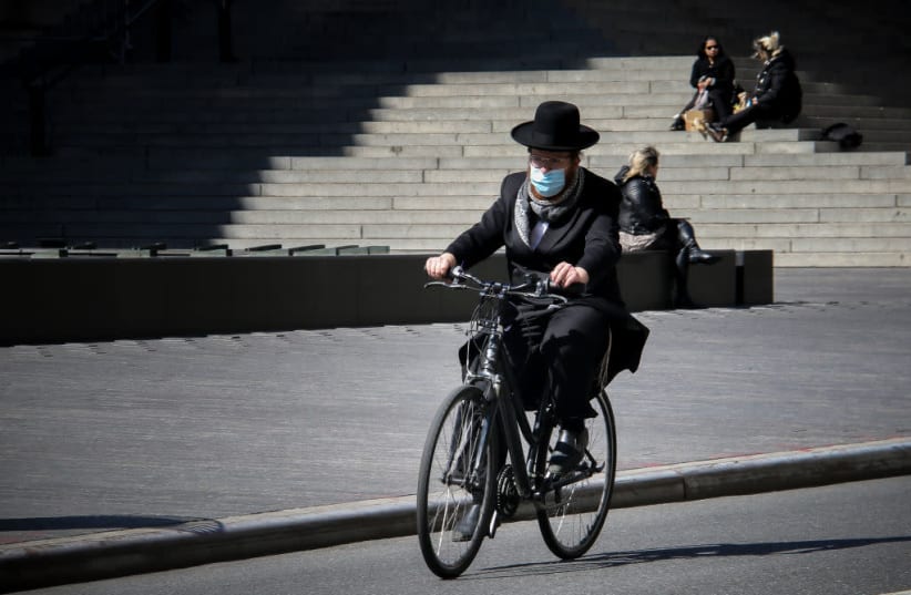 An Orthodox Jewish man wearing a surgical mask rides by the Metropolitan Museum of Art in New York City, April 22, 2020. (photo credit: ERICA PRICE/GETTY IMAGES)