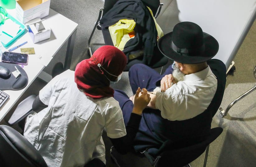 People get vaccinated at the Clalit vaccination center in Jerusalem, January 3, 2020. (photo credit: MARC ISRAEL SELLEM/THE JERUSALEM POST)