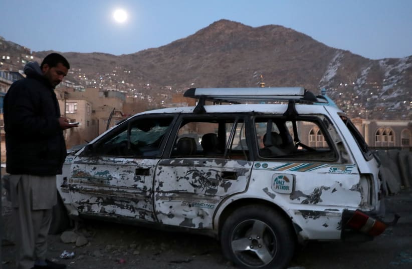 An Afghan man inspects a damaged car after a bomb blast in Kabul, Afghanistan December 28, 2020. (photo credit: OMAR SOBHANI / REUTERS)