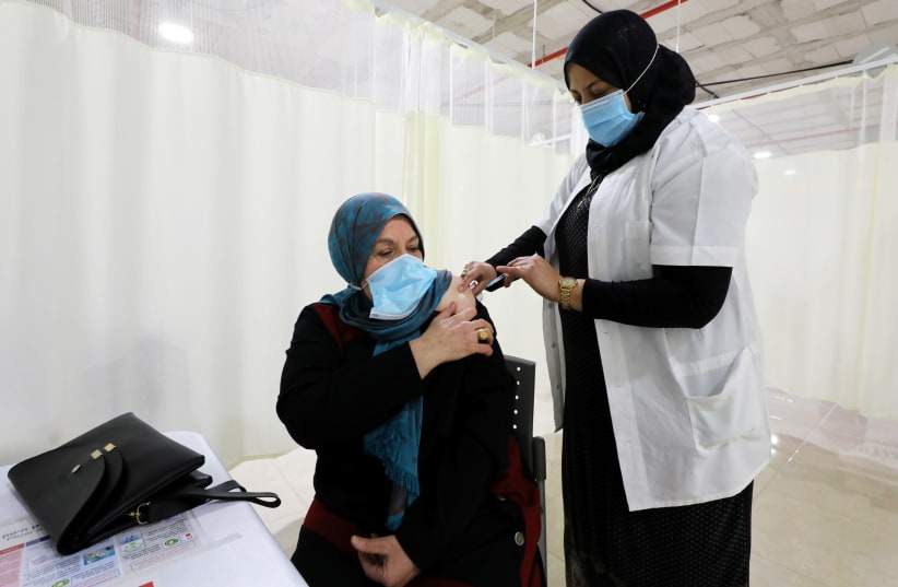 A woman receives a vaccination against the coronavirus disease (COVID-19) at a vaccination center in Umm El-Fahem, Israel January 3, 2021 (photo credit: REUTERS/AMMAR AWAD)