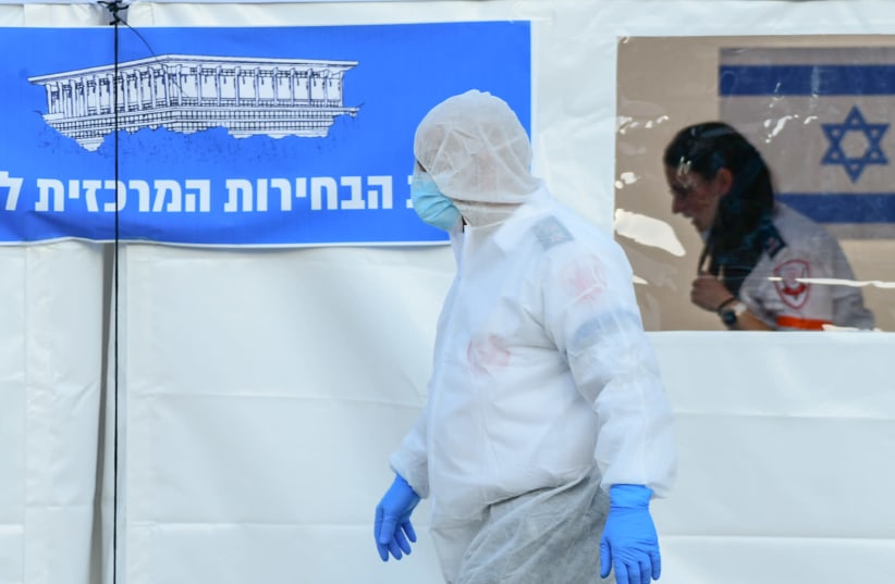 People arriving to cast their votes and and workers are seen at a special polling station for voters quarantined due to possible exposure to the new coronavirus in Tel Aviv, during the Knesset Elections, on March 2, 2020.  (photo credit: TOMER NEUBERG/FLASH90)
