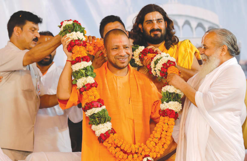 SUPPORTERS OF Yogi Adityanath (center), chief minister of India’s most populous state of Uttar Pradesh, present him with a garland on the birthday of Nritya Gopal Das, a famous Hindu priest, in Ayodhya, in 2017. (photo credit: PAWAN KUMA/REUTERS)