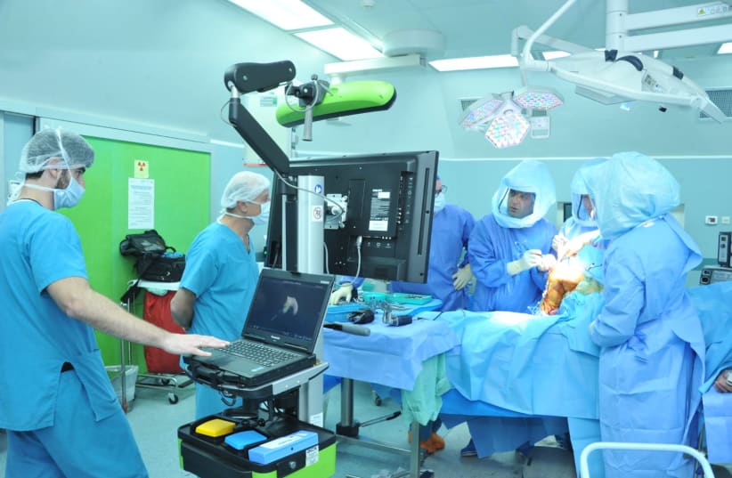 Doctors performing a surgery via the guidance of a robot.  (photo credit: Courtesy)