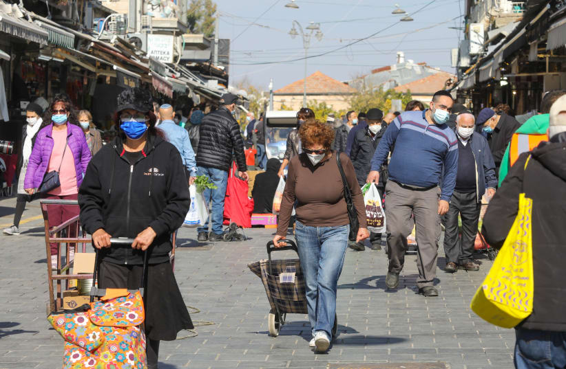 Israelis are seen walking in Jerusalem's Mahane Yehuda market amid the coronavirus pandemic, on January 6, 2021. (photo credit: MARC ISRAEL SELLEM/THE JERUSALEM POST)