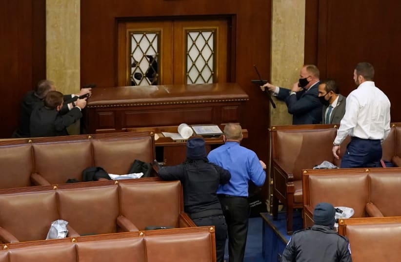 JANUARY 06: U.S. Capitol police officers point their guns at a door that was vandalized in the House Chamber during a joint session of Congress on January 06, 2021 in Washington, DC. Congress held a joint session today to ratify President-elect Joe Biden's 306-232 Electoral College win over Presiden (photo credit: DREW ANGERER/GETTY IMAGES)