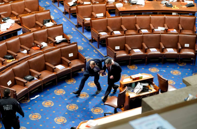 Members of Congress run for cover as protesters try to enter the House Chamber during a joint session of Congress on January 06, 2021 in Washington, DC to ratify President-elect Joe Biden's 306-232 Electoral College win over President Donald Trump. (photo credit: DREW ANGERER/GETTY IMAGES)