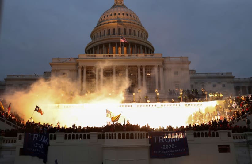 An explosion caused by a police munition is seen while supporters of US President Donald Trump gather in front of the US Capitol Building in Washington (photo credit: LEAH MILLIS/REUTERS)