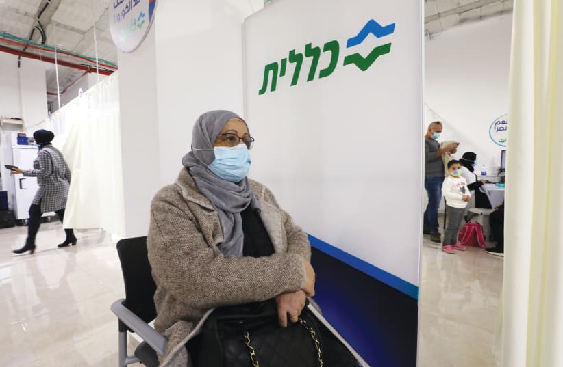 A WOMAN waits to receive a vaccination against coronavirus in Umm el-Fahm on Sunday. (photo credit: AMMAR AWAD/REUTERS)
