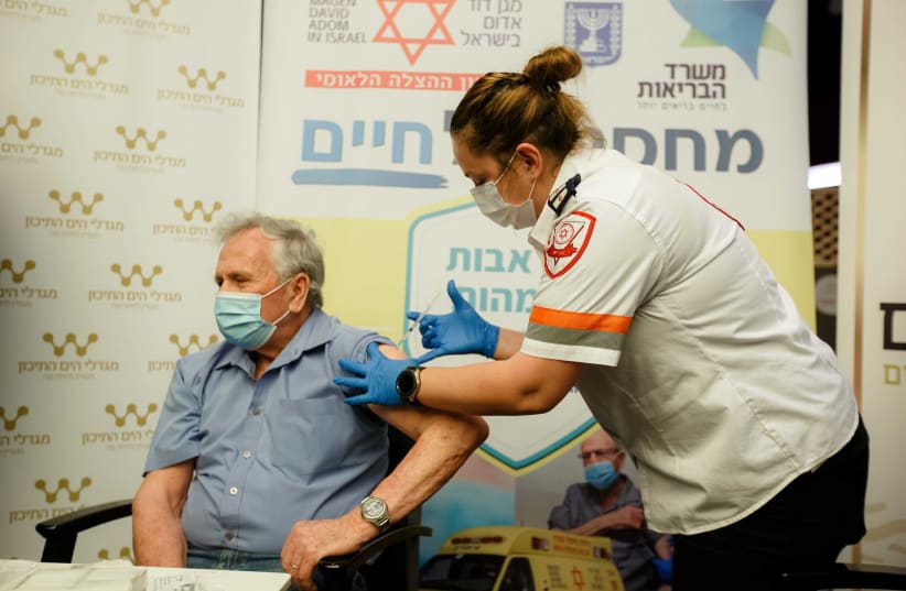 An MDA volunteer vaccinates an elderly man against the novel coronavirus. (photo credit: MDA)