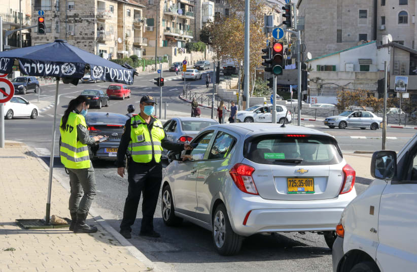 Police are seen checking drivers at a coronavirus checkpoint near Jerusalem's Gan Sacher amid lockdown, on January 12, 2021. (photo credit: MARC ISRAEL SELLEM/THE JERUSALEM POST)