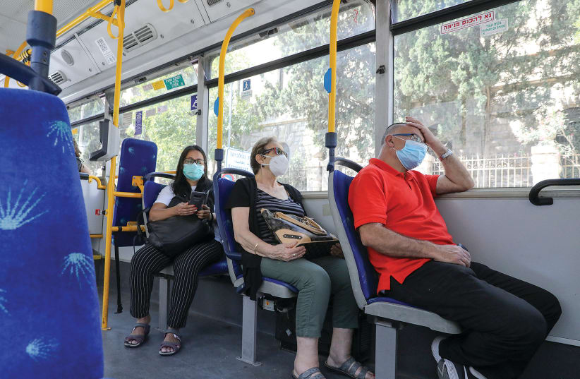 Passengers wear masks as they travel on a bus. (photo credit: MARC ISRAEL SELLEM)