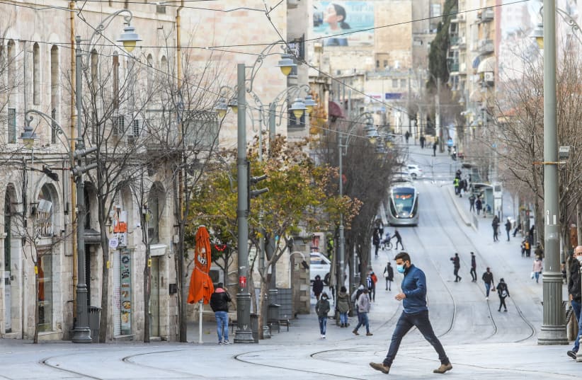 Israelis are seen walking along the Jaffa Street light rail tracks in Jerusalem amid the ongoing coronavirus lockdown, on January 14, 2021.. (photo credit: MARC ISRAEL SELLEM/THE JERUSALEM POST)