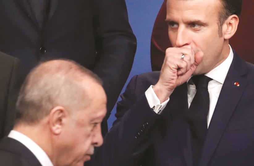 French President Macron, coughs as Turkish President Recep Tayyip Erdogan walks by. (photo credit: CHRISTIAN HARTMANN/REUTERS)