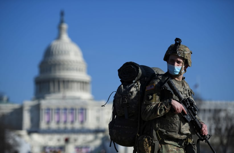 A member of the National Guard mounts guard near the US Capitol building, as the House of Representatives debates impeaching US President Donald Trump a week after his supporters stormed the Capitol building in Washington, US, January 13, 2021 (photo credit: REUTERS/BRANDON BELL)