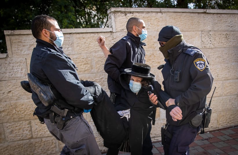 Police officers during a raid on a Yeshiva that is open in violation of the Covid-19 emergency regulations, at the Sanhedria Neighborhood in Jerusalem, January 19, 2021. (photo credit: YONATAN SINDEL/FLASH90)