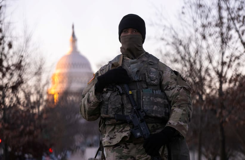 A member of the National Guard stands watch outside the U.S. Capitol at sunrise on President-elect Joe Biden's Inauguration Day in Washington, U.S., January 20, 2021. (photo credit: CAITLIN OCHS/REUTERS)