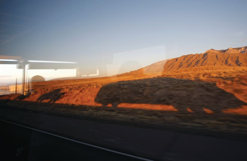A BUS in Democratic presidential candidate Barack Obama’s motorcade casts its shadow on a mountain, en route to Santa Fe in 2008. Cameron says her escape from loud New York to quieter Santa Fe inspired her book.  (photo credit: JASON REED/REUTERS)