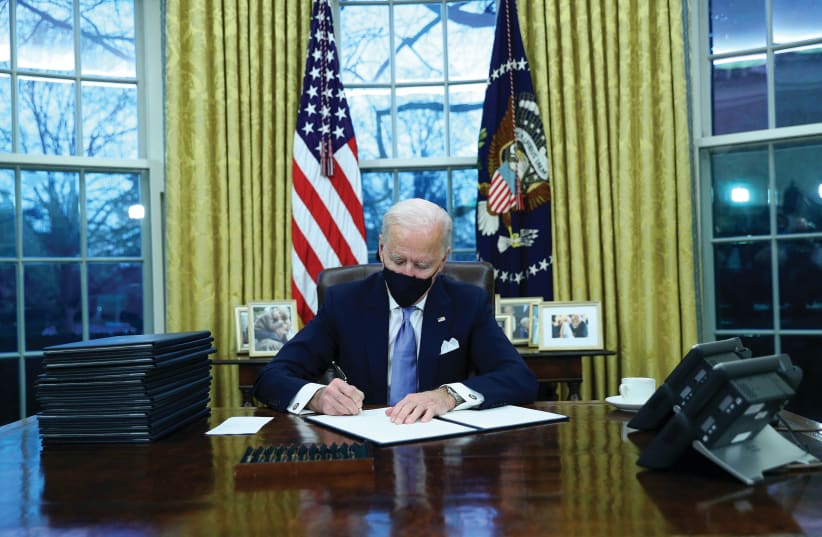 US PRESIDENT Joe Biden signs executive orders in the Oval Office of the White House on Wednesday, after his inauguration as the 46th president of the United States. (photo credit: TOM BRENNER/REUTERS)