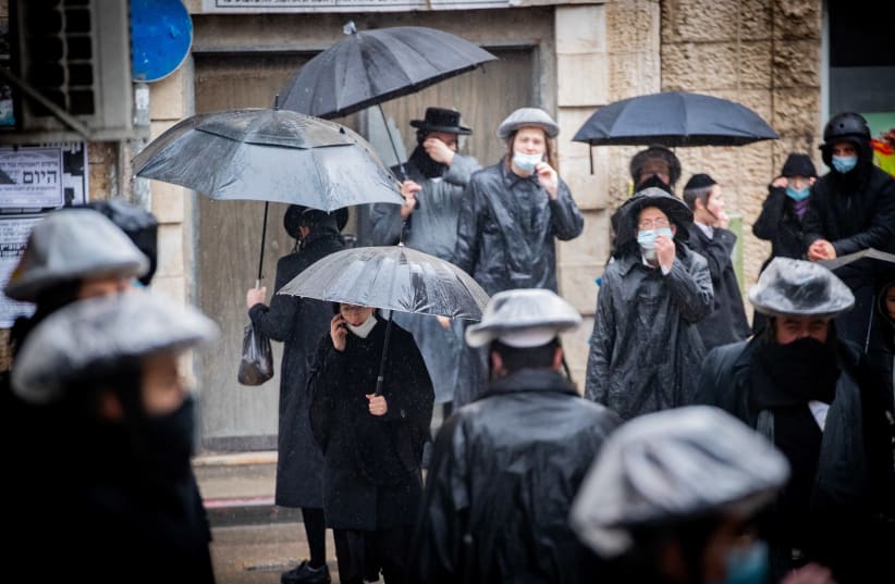 Ultra-Orthodox Jews seen in the street of the ultra-Orthodox neighborhood of Mea Shearim on a rainy day, January 18, 2021.  (photo credit: YONATAN SINDEL/FLASH 90)