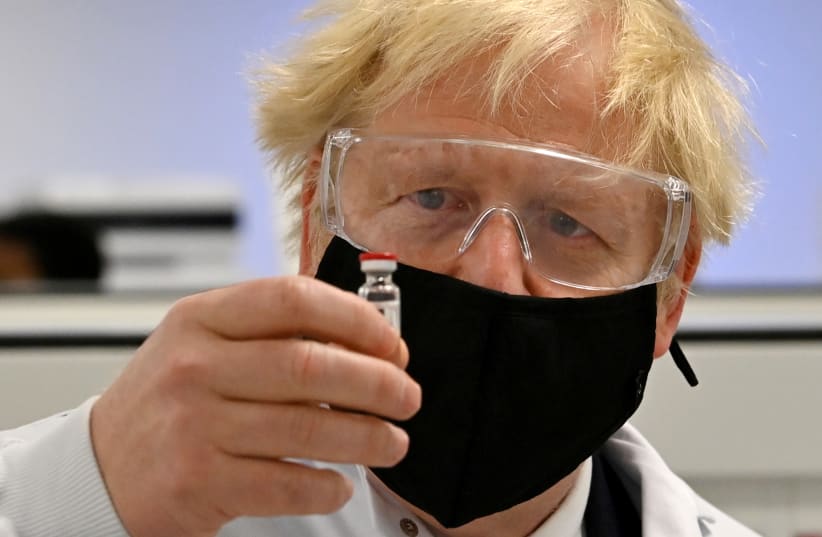 Britain's Prime Minister Boris Johnson poses for a photograph with a vial of the AstraZeneca/Oxford University COVID-19 candidate vaccine, known as AZD1222, at Wockhardt's pharmaceutical manufacturing facility in Wrexham, Wales, Britain November 30, 2020. (photo credit: PAUL ELLIS/ REUTERS)