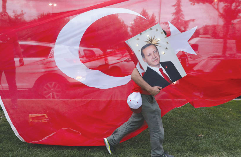 A SUPPORTER of Turkish President Recep Tayyip Erdogan holds his picture in front of Turkey’s flag at the ruling AK Party headquarters in Istanbul. (photo credit: GORAN TOMASEVIC/REUTERS)