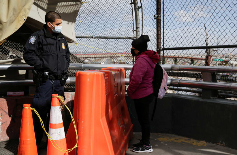 A migrant from Guatemala talk to a US Customs and Border Protection (CBP) agent at the Paso del Norte international border bridge to request asylum in El Paso, Texas, U.S., in Ciudad Juarez, Mexico January 26, 2021.  (photo credit: REUTERS/JOSE LUIS GONZALEZ)