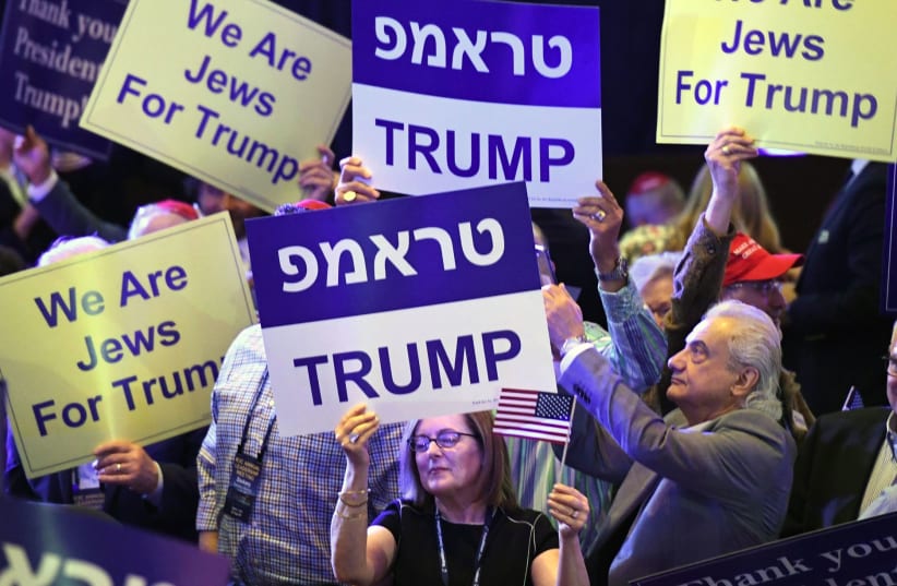 Attendees at the Republican Jewish Coalition's annual leadership meeting hold up signs while waiting to see President Donald Trump speak at The Venetian Las Vegas (photo credit: GABE FRIEDMAN (JTA))