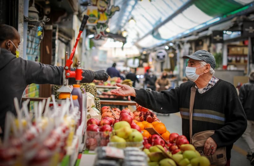 A man is seen at a produce stand at Jerusalem's Mahane Yehuda market during Israel's third lockdown. (photo credit: MARC ISRAEL SELLEM/THE JERUSALEM POST)