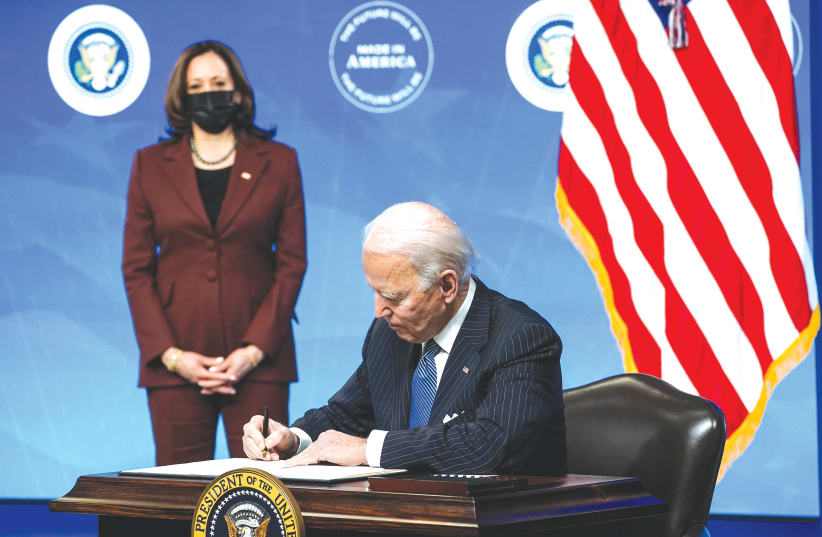 US PRESIDENT Joe Biden signs an executive order as Vice President Kamala Harris watches, at the White House in Washington, DC, on January 25. (photo credit: KEVIN LAMARQUE/REUTERS)