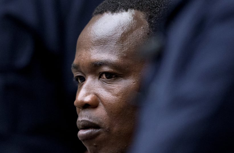 Dominic Ongwen, a senior commander in the Lord's Resistance Army, whose fugitive leader Kony is one of the world's most-wanted war crimes suspects, is flanked by two security guards as he sits in the court room of the International Court in The Hague, Netherlands, December 6, 2016.  (photo credit: PETER DEJONG/REUTERS)