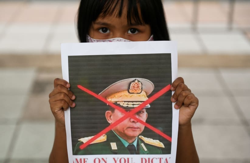 A girl holds a picture of Myanmar's army chief Min Aung Hlaing with his face crossed out as Myanmar citizens protest against the military coup in Myanmar outside United Nations venue in Bangkok, Thailand February 6, 2021.  (photo credit: CHALINEE THIRASUPA/REUTERS)