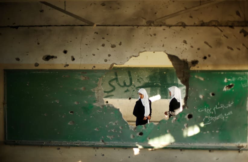 Palestinian students look inside a classroom that witnesses said was shelled by Israel during its offensive, on the first day of the new school year east of Gaza City September 14, 2014. (photo credit: SUHAIB SALEM/REUTERS)