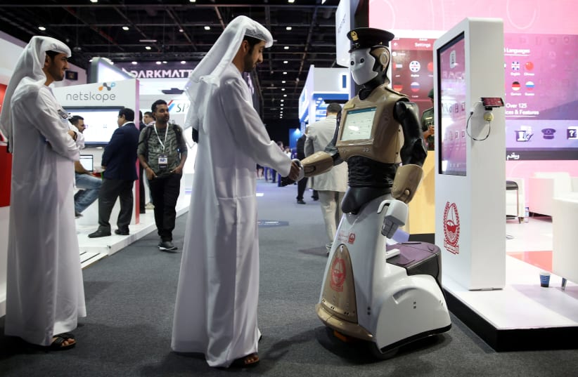 Visitor shakes hands with an operational robot policeman at GISEC in Dubai (photo credit: REUTERS/STRINGER)