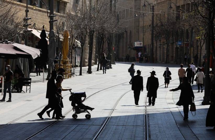 Israelis are seen walking along the light rail tracks on Jerusalem's Jaffa Street amid the coronavirus pandemic, on February 10, 2021. (photo credit: MARC ISRAEL SELLEM/THE JERUSALEM POST)