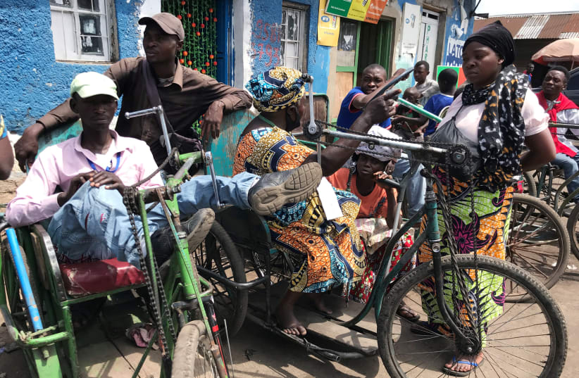Disabled couriers sits on their tricycles as they wait to transport grocery at the no-man's-land amid the coronavirus disease (COVID-19) outbreak between Rwanda and Congo in Goma, Democratic Republic of Congo November 20, 2020 (photo credit: REUTERS/DJAFFAR AL-KATANY)