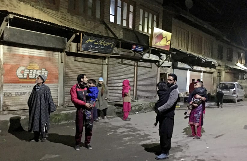 Residents carrying their children stand on a road after vacating their houses following an earthquake in Srinagar February 12, 2021.  (photo credit: REUTERS/STRINGER)